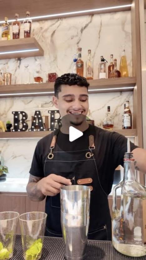 Rey smiling behind the bar, shaking a cocktail