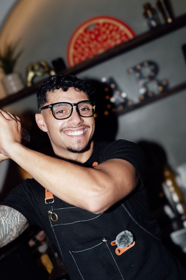 Rey Estevez grinning mid-shake in his black BW apron